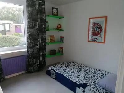 a bedroom with a bed and a window and shelves at Rent & Relax in Mol