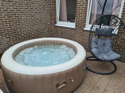a hot tub with a chair next to a building at Rent & Relax in Mol