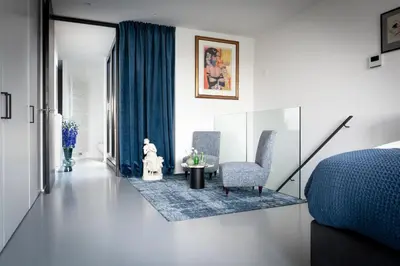 a bedroom with a bed and a chair and a table at Suite Aux Anges in Antwerp