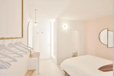 a white bedroom with a bed and a mirror at Urban Walls in Brussels