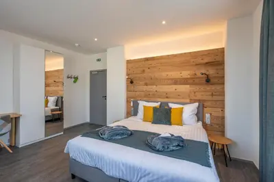 a bedroom with a large bed with a wooden wall at Hotel Fi'Lin in Machelen