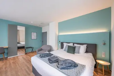a bedroom with a large bed with a blue wall at Hotel Fi'Lin in Machelen