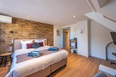 a bedroom with a large bed and a brick wall at Hotel Fi'Lin in Machelen