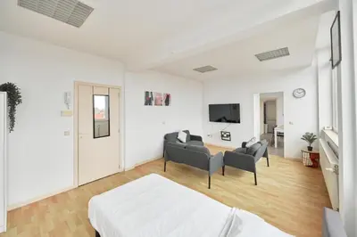a white bedroom with a bed and a living room at BoLofts in Antwerp