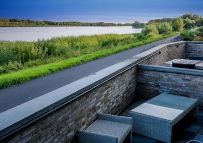 two benches on a brick wall with a view of a river at Scheldeoever in Temse