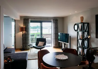 a living room with a table and a tv at Scheldeoever in Temse