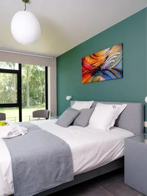 a bedroom with a large bed with a painting on the wall at b & b St-Hubert in Sint-Martens-Lennik