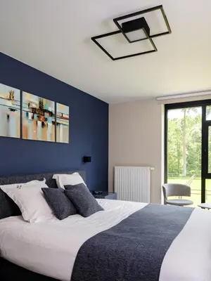 a bedroom with a large bed with a blue wall at b & b St-Hubert in Sint-Martens-Lennik