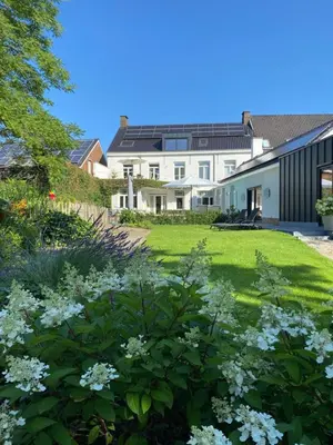 a garden with white flowers in front of a house at B&B Tannerie in Balen