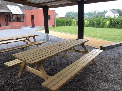 two wooden picnic tables sitting under a pavilion at Tussenbeke in Lede