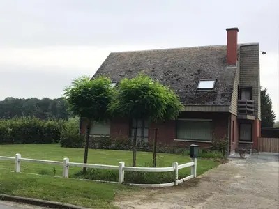 a house with a white fence and two palm trees at Tussenbeke in Lede