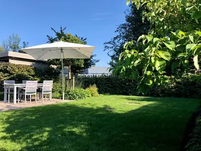 a table and chairs under an umbrella in a yard at Het Nekkerhof B&Bio in Mechelen