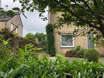 a garden in front of a brick building with a window at Het Nekkerhof B&Bio in Mechelen
