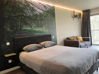 a bedroom with a bed with a large painting on the wall at Bleekhoeve in Olen