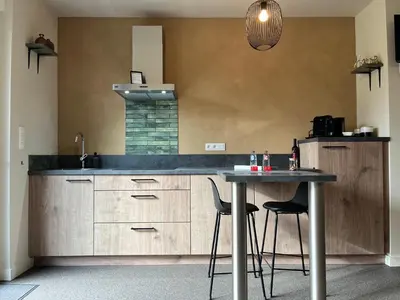 a kitchen with a counter and a table with chairs at Bleekhoeve in Olen