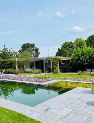 a garden with a pond in front of a building at Lit de Clémot in Merelbeke