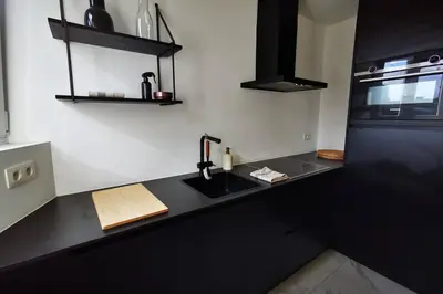 a kitchen with a black counter top with a sink at De Flat - Licht en luxueus appartement bij Het Zuid in Antwerp