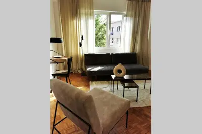 a living room with a black couch and a table at De Flat - Licht en luxueus appartement bij Het Zuid in Antwerp