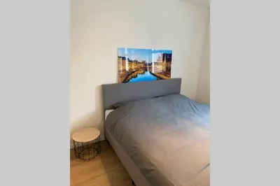 a bedroom with a bed with a picture on the wall at Schitterend nieuwbouw appartement in Gent in Ghent