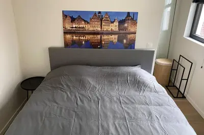 a bedroom with a bed with a picture on the wall at Schitterend nieuwbouw appartement in Gent in Ghent