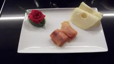 a white plate with a piece of cheese and a red rose at Art de Sejour - B&B in Brussels