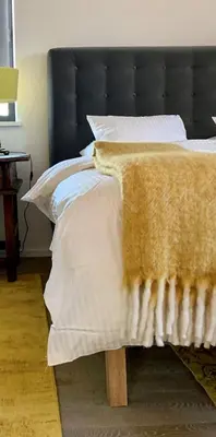 a bed with a black headboard with a blanket on it at b&b Meilrijk in Diest