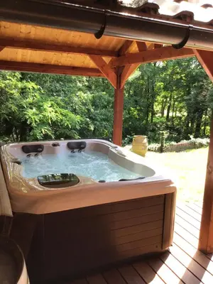 a hot tub sitting under a pergola on a deck at Charming house in the woods with private wellness in Schilde
