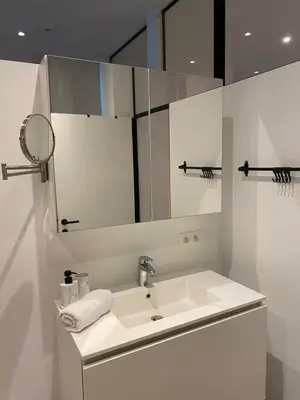 a white bathroom with a sink and a mirror at Charming modern apartment in the heart of Antwerp with optional private parking in Antwerp