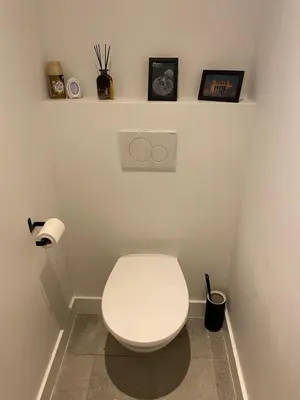a white toilet in a bathroom with two shelves at Charming modern apartment in the heart of Antwerp with optional private parking in Antwerp