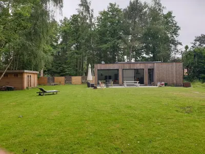 a small building in a yard with a grass field at Eden in Sint-Pauwels