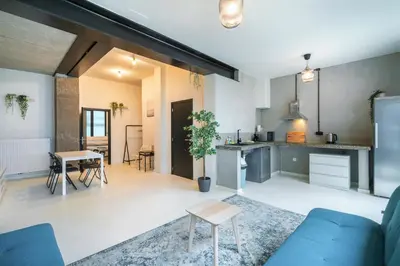 a living room with a blue couch and a kitchen at Antwerps Central Residence in Antwerp