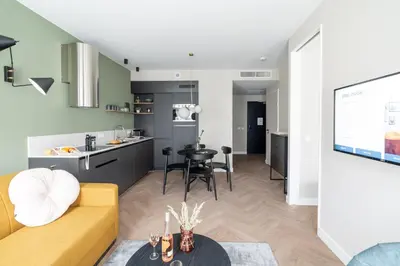 a living room with a yellow couch and a kitchen at YAYS Antwerp Opera by Numa in Antwerp