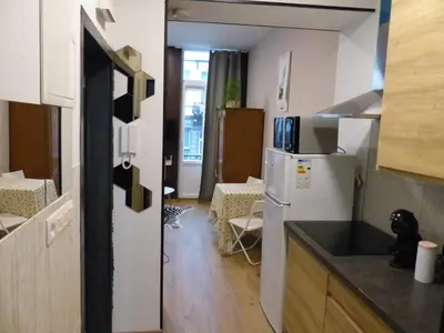 a small kitchen with a refrigerator and a table at Superbe Studio au 1er étage, proche de la gare du Midi in Brussels