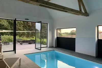 a swimming pool in a house with glass doors at Domein Warandehof in Gooik