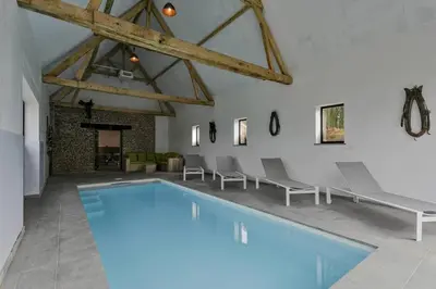 a large swimming pool in a room with chairs at Domein Warandehof in Gooik