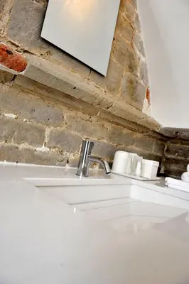 a white sink in front of a brick wall at Guesthouse Bernardin in Antwerp