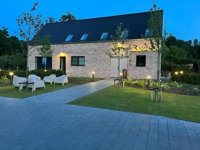 a brick building with white chairs and a patio at Ramslo in Herselt