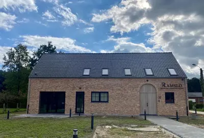 a red brick building with a black roof at Ramslo in Herselt
