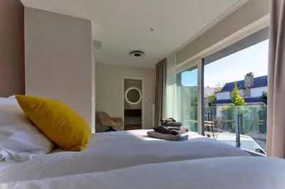 a bedroom with a white bed and a large window at BEUKENHOUSE in Drogenbos
