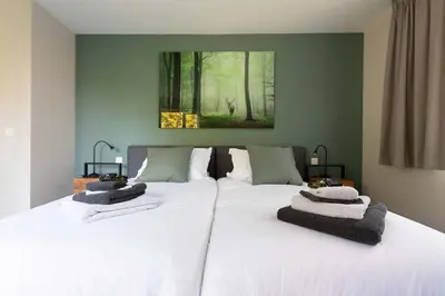 a bedroom with a large bed with white sheets at BEUKENHOUSE in Drogenbos