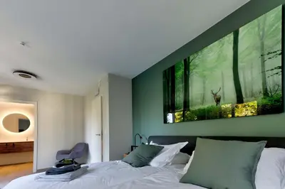 a bedroom with a bed with a painting on the wall at BEUKENHOUSE in Drogenbos