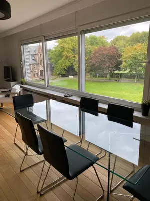 a glass table and chairs in a room with a window at Lichtrijk mooi appartement met zicht op hof van Roosendael in Antwerp