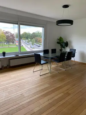 a dining room with a table and chairs and a large window at Lichtrijk mooi appartement met zicht op hof van Roosendael in Antwerp