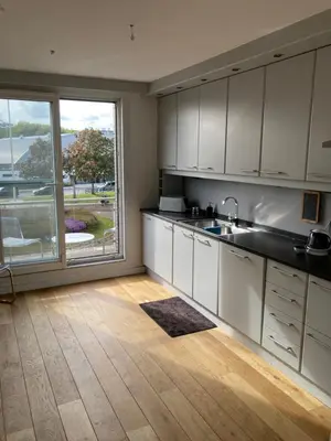 a kitchen with white cabinets and a large window at Lichtrijk mooi appartement met zicht op hof van Roosendael in Antwerp