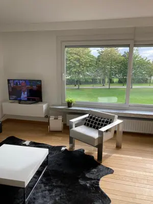 a living room with a large window and a tv at Lichtrijk mooi appartement met zicht op hof van Roosendael in Antwerp