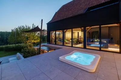 a hot tub on a patio with a house at Wellness Suite B&B L'O Reine in Sint-Pieters-Leeuw