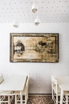 a painting hanging on a wall with two tables at La Maison Haute guesthouse in Brussels