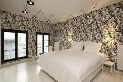 a bedroom with a white bed and a black and white wall at La Maison Haute guesthouse in Brussels