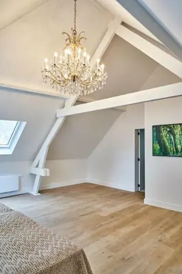 a chandelier in a room with white walls and wooden floors at Moleneinde 10 in Weelde