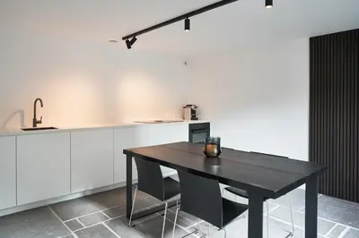 a kitchen with a black table and some white cabinets at Moleneinde 10 in Weelde